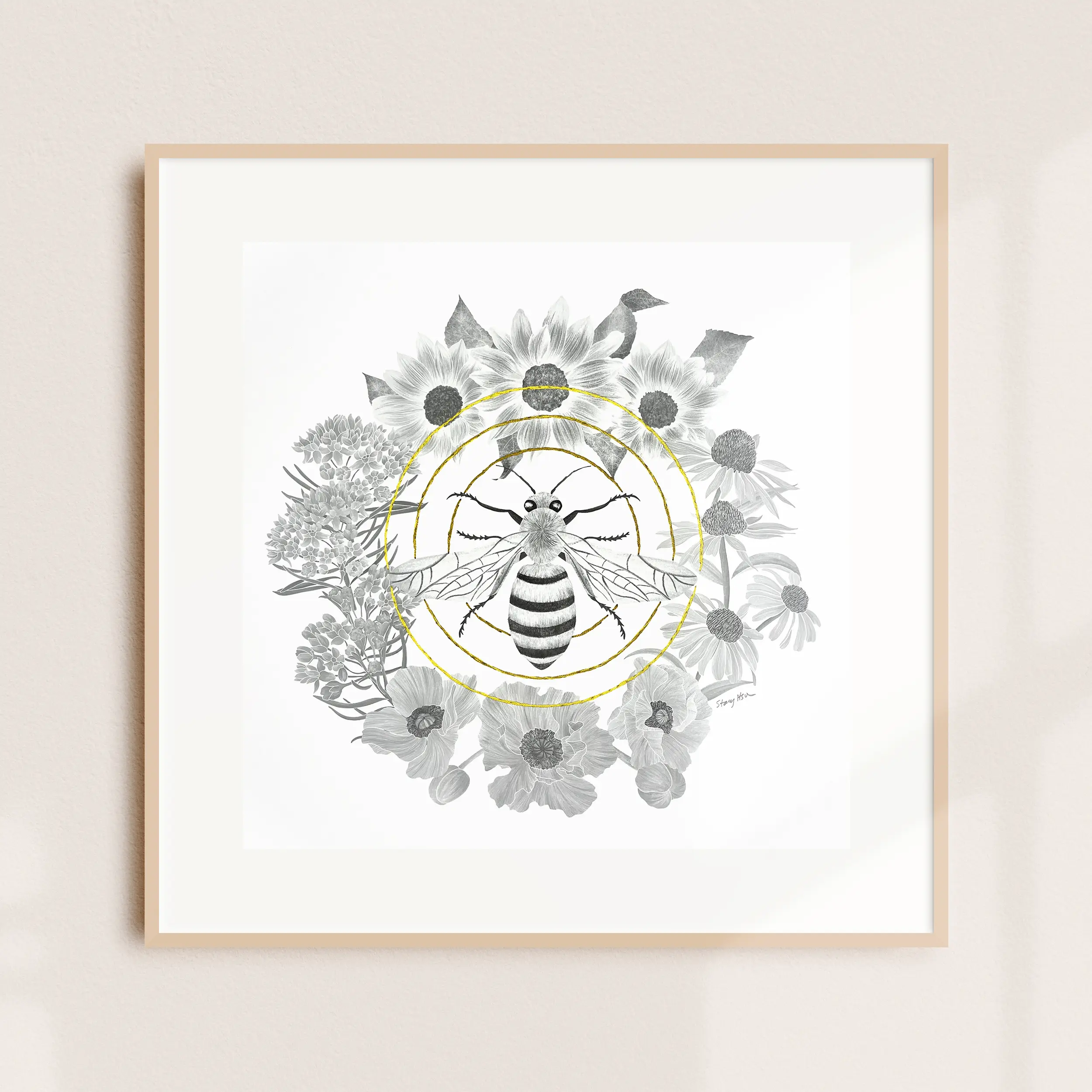 A framed illustration of a bee amid a floral wreath