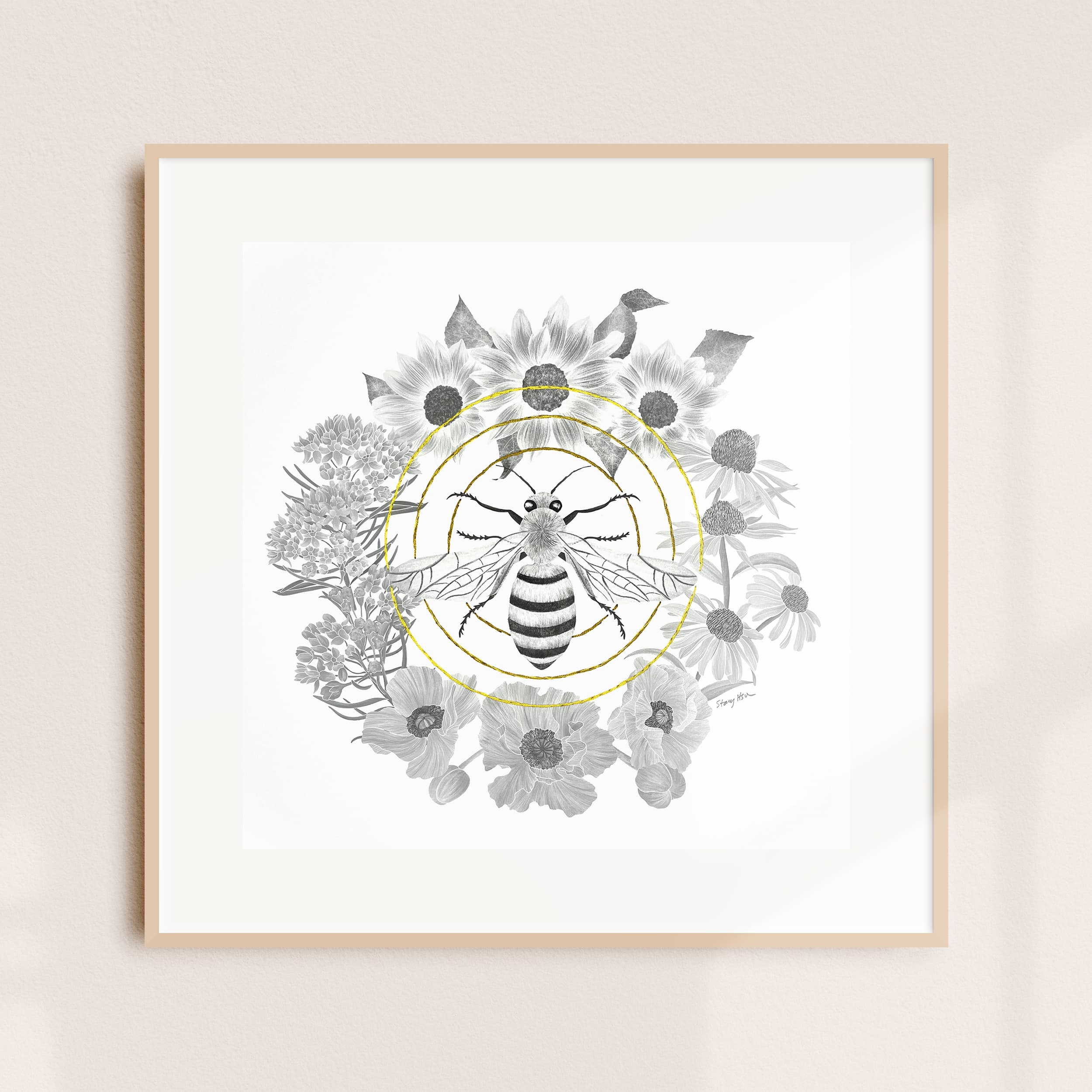 A framed illustration of a bee amid a floral wreath