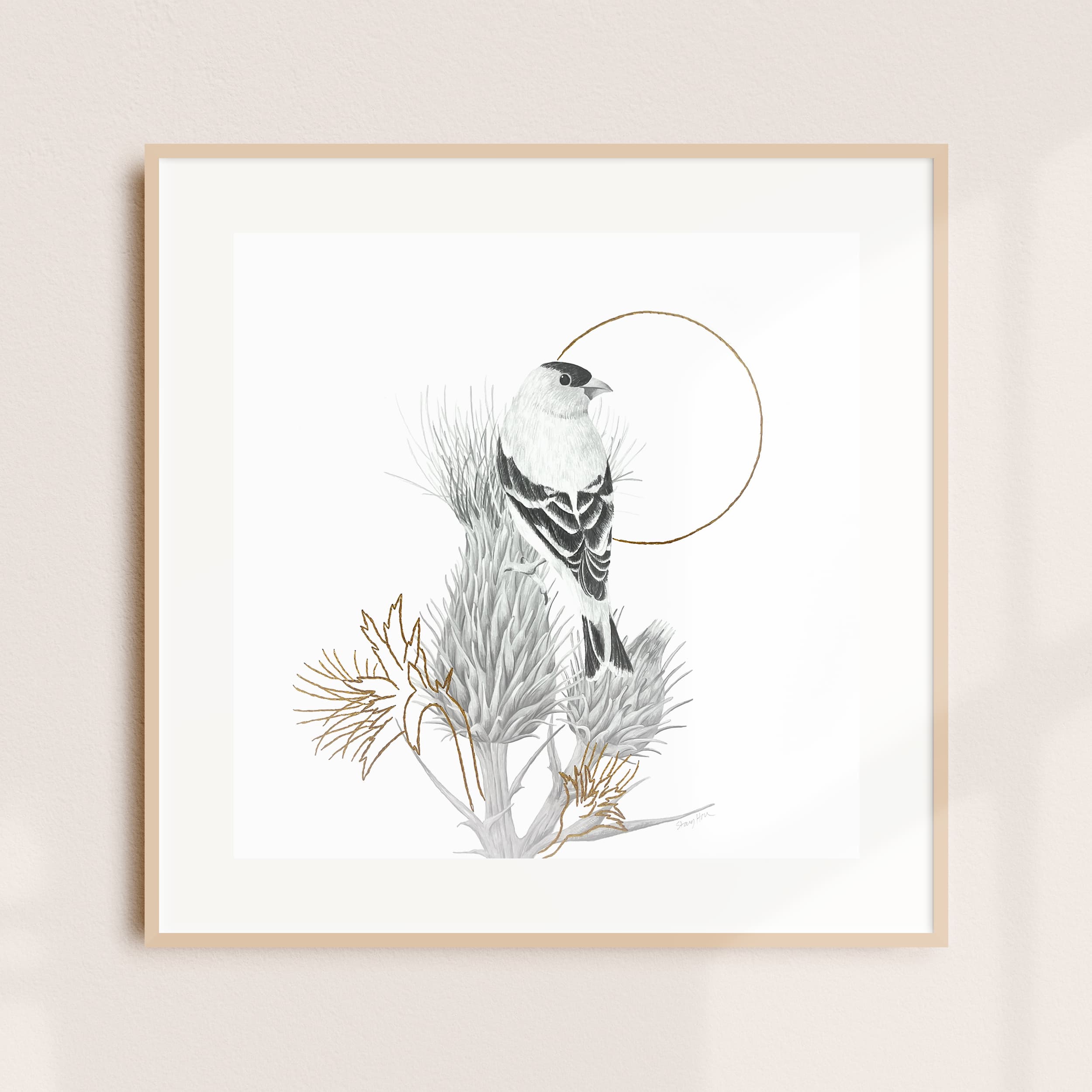 A framed illustration of a small bird perched on a thistle branch with a golden ring behind it