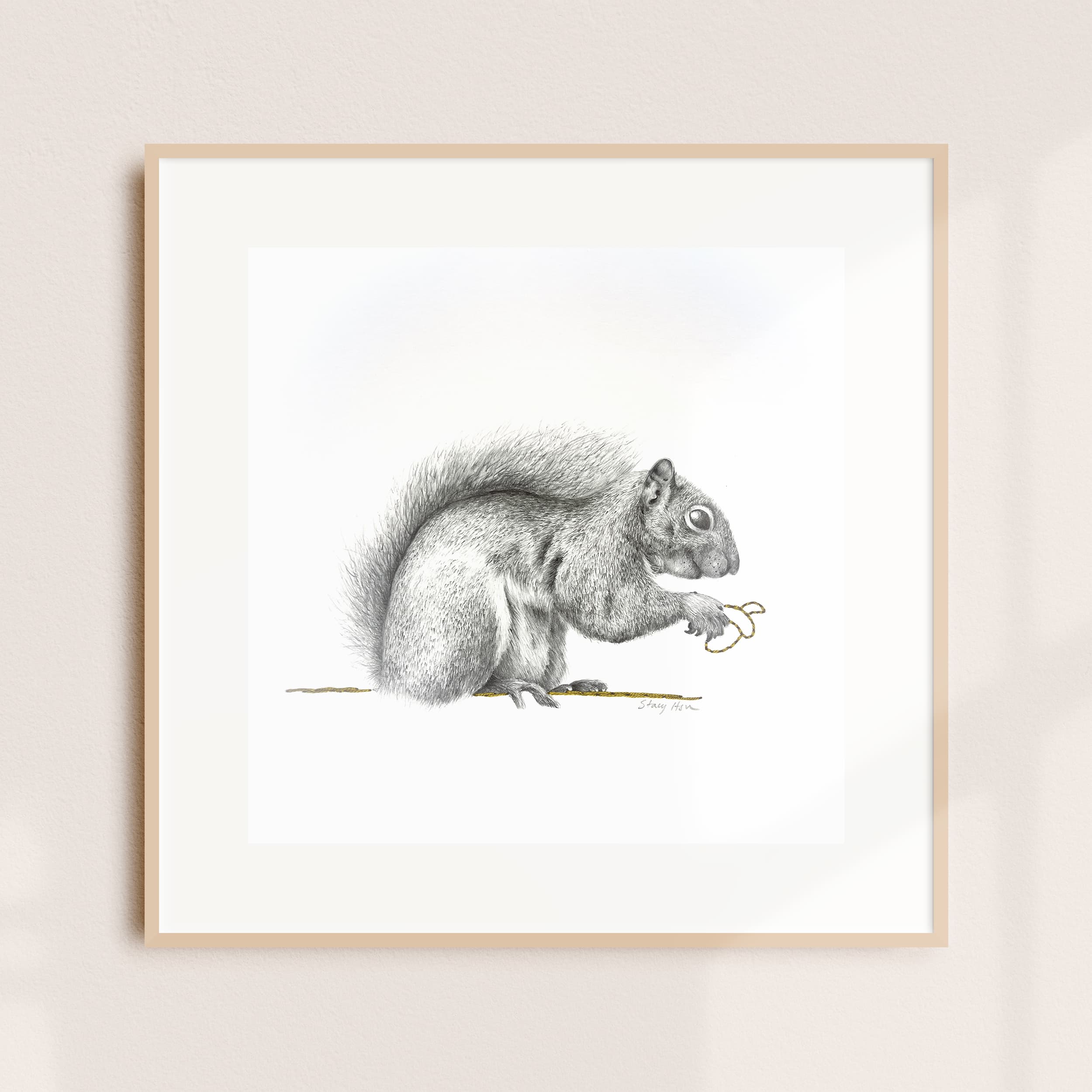 A framed illustration of an eastern gray squirrel holding a length of golden thread
